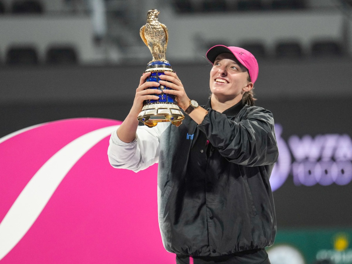 Iga Swiatek celebrates with the winner's trophy.