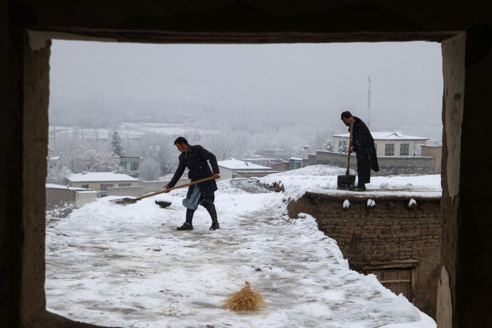 Afghan men shovel snow from the rooftop of a house following snowfall in Fayzabad, Badakhshan province on February 19, 2024. (Photo by Omer Abrar / AFP)