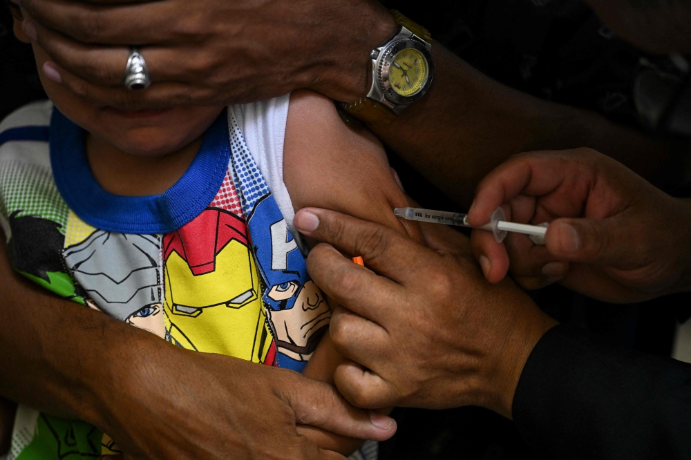 (Files) A boy accompanied by his father receives a dose of the measles and rubella vaccine from medical personnel at a community health center in the Lidice neighborhood of Caracas, on August 17, 2022. (Photo by Yuri Cortez / AFP)