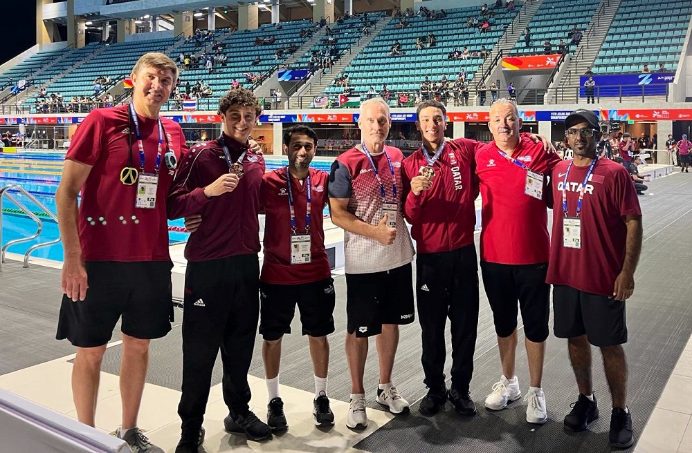 Qatar's swimmers along with the officials celebrate with their medals.  