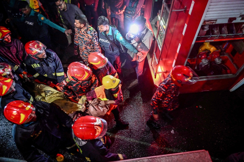 Firefighters carry an injured person during rescue operations following a fire in a commercial building that killed at least 43 people, in Dhaka, on February 29, 2024. (Photo by Munir Uz Zaman / AFP)