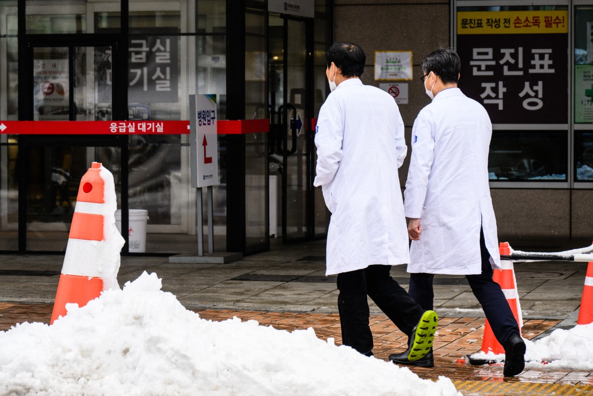 Medical workers walk outside a hospital after snowfall in Seoul on February 22, 2024. Photo by ANTHONY WALLACE / AFP

