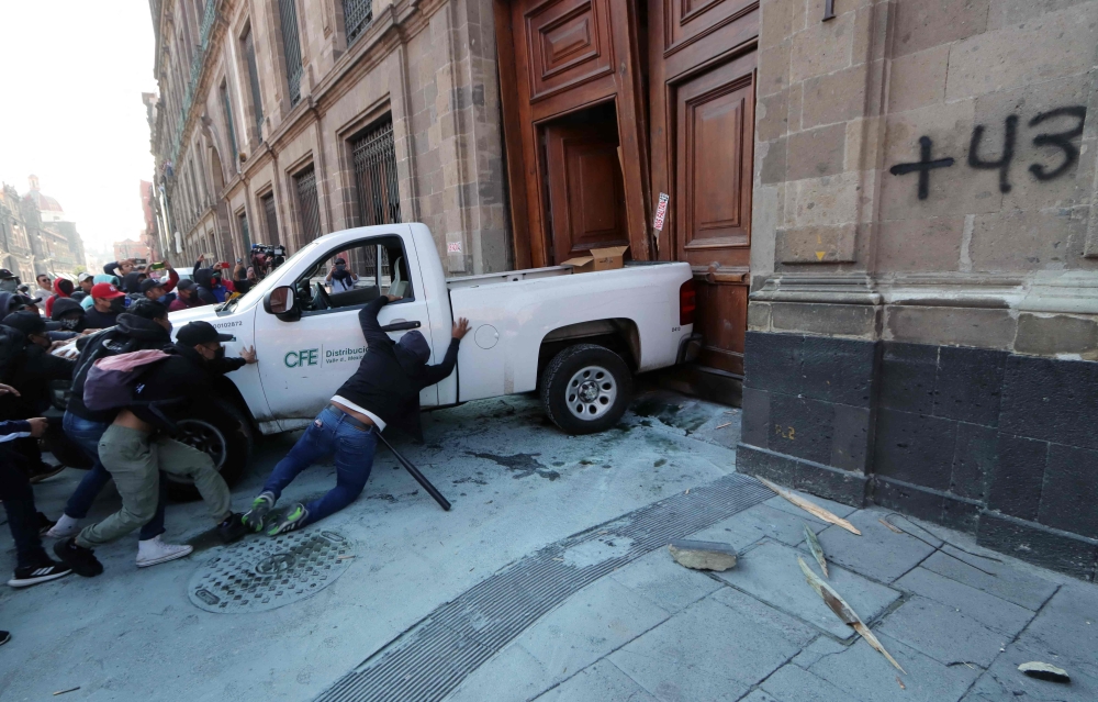 Demonstrators push a pickup truck to break down a presidential palace door in Mexico City on March 6, 2024, during a protest over the disappearance of the 43 students of the Ayotzinapa teaching training school in 2014. (Photo by Valentina Alpide / AFP)