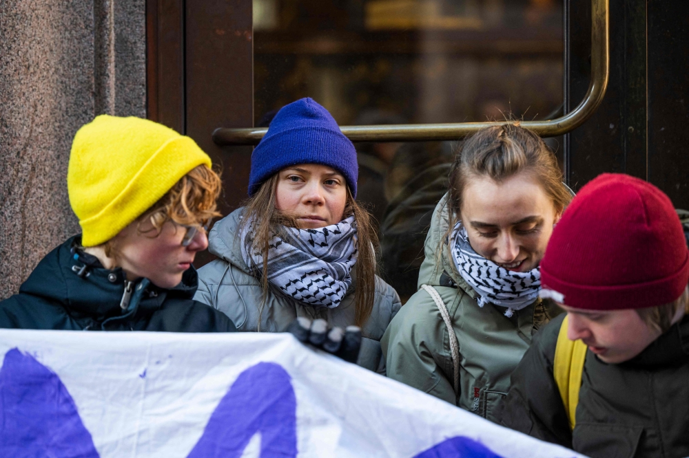 Swedish climate activist Greta Thunberg (2nd L) and a group of fellow activists block the main entrances of the Swedish Parliament during a protest due to the lack of action from the Swedish authorities, on March 11, 2024, in Stockholm, Sweden. (Photo by Jonathan NACKSTRAND / AFP)
