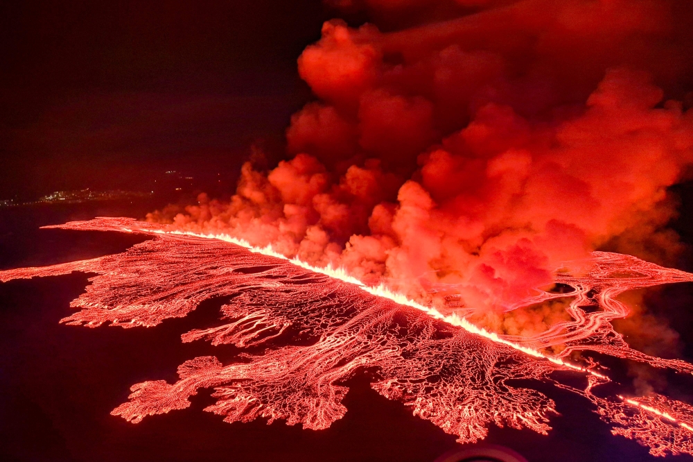This handout picture released by the Icelandic Coast Guard on March 16, 2024 shows billowing smoke and flowing lava pouring out of a new fissure, during a surveilance flight above a new volcanic eruption on the outskirts of the evacuated town of Grindavik, western Iceland. Photo by HANDOUT / Icelandic Coast Guard / AFP