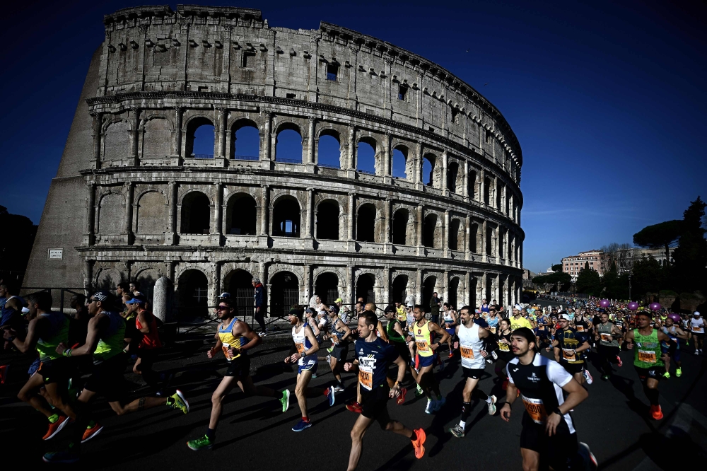 Competitors run by the Colosseum, during the Rome Marathon in Rome, on March 17, 2024. (Photo by Filippo MONTEFORTE / AFP)