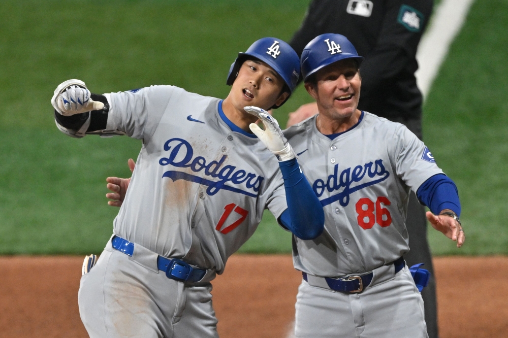 Los Angeles Dodgers' Shohei Ohtani (L) celebrates with 1B coach Clayton McCullough (R) on first base after hitting a RBI single during the eighth inning of the 2024 MLB Seoul Series baseball game between Los Angeles Dodgers and San Diego Padres at the Gocheok Sky Dome in Seoul on March 20, 2024. (Photo by Jung Yeon-je / AFP)