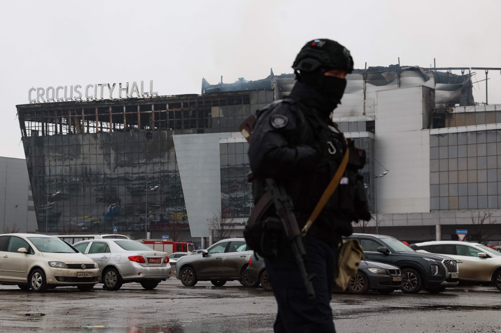 A law enforcement officer patrols the scene of the gun attack at the Crocus City Hall concert hall in Krasnogorsk, outside Moscow, on March 23, 2024. (Photo by Stringer / AFP)