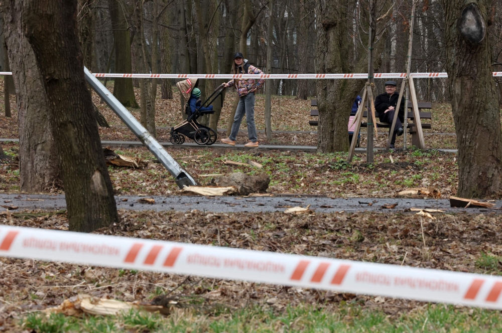 Local residents walk near the site of a rocket strike in one of the parks after a Russian missile attack in Kyiv, on March 24, 2024, amid the Russian invasion in Ukraine. Photo by Anatolii STEPANOV / AFP.
