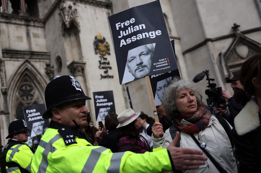 Police officers stand guard as supporters of WikiLeaks founder Julian Assange hold placards outside The Royal Courts of Justice, Britain's High Court, in central London on March 26, 2024. (Photo by Daniel LEAL / AFP)
