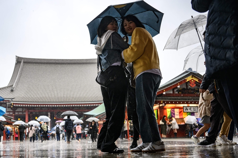 People walk with their umbrellas during a rainy day at Sensoji Temple, a popular tourist location, in Tokyo's Asakusa district on March 26, 2024. (Photo by Philip FONG / AFP)