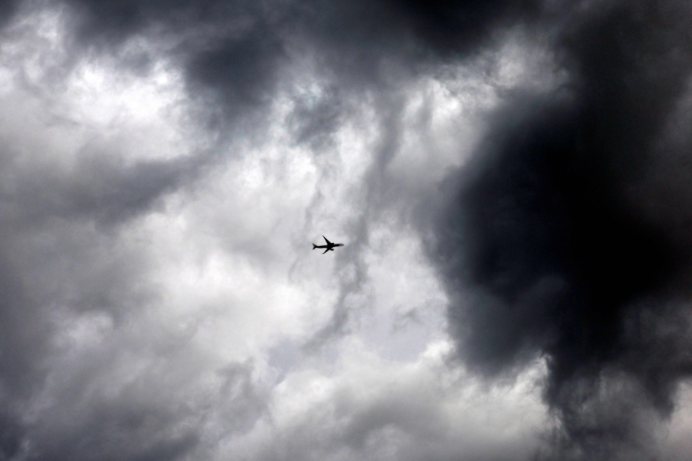 A picture taken on March 27, 2024 shows an aircraft flying amid clouds while entering Madrid airport. (Photo by OSCAR DEL POZO / AFP)