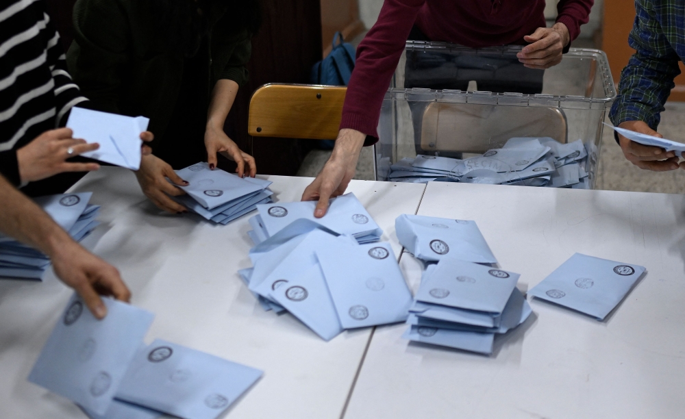 Electoral workers begin to count ballots at a polling station following municipal elections across Turkiye, in Istanbul on March 31, 2024. (Photo by YASIN AKGUL / AFP)
