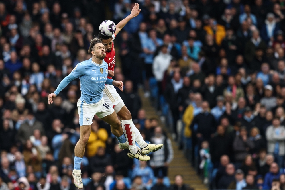 Manchester City's English midfielder #10 Jack Grealish (L) fights for the ball with Arsenal's French defender #02 William Saliba (R) during the English Premier League football match between Manchester City and Arsenal at the Etihad Stadium in Manchester, north west England, on March 31, 2024. (Photo by Darren Staples / AFP)
