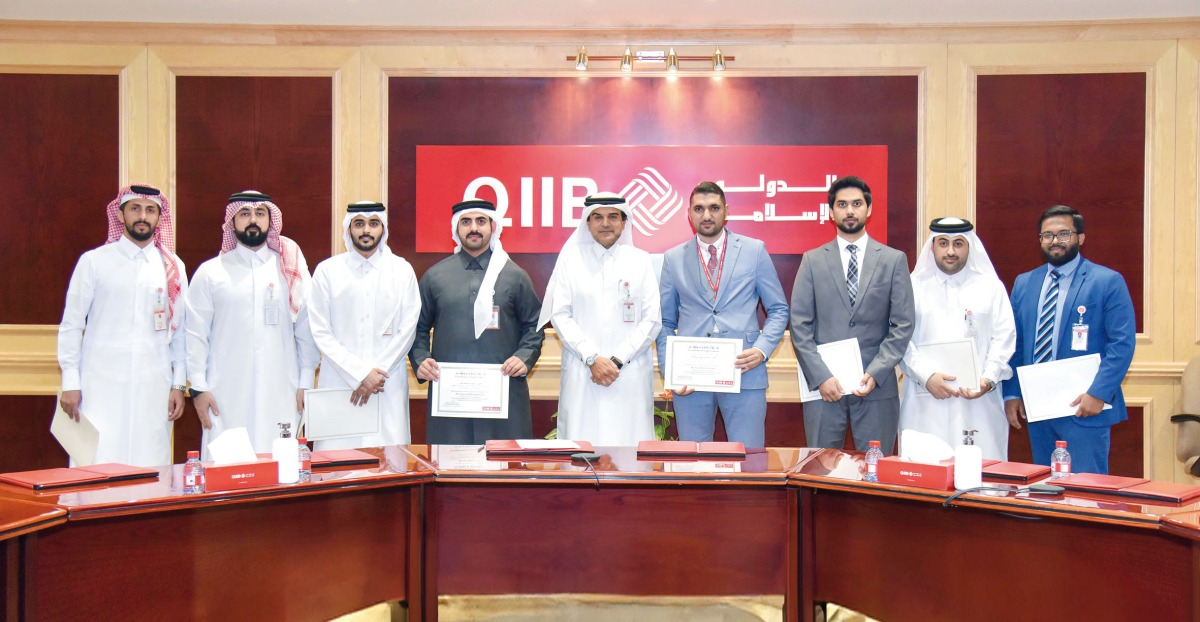 QIIB Chief Executive Officer Dr. Abdulbasit Ahmad Al Shaibei poses with employees during the honouring ceremony. 