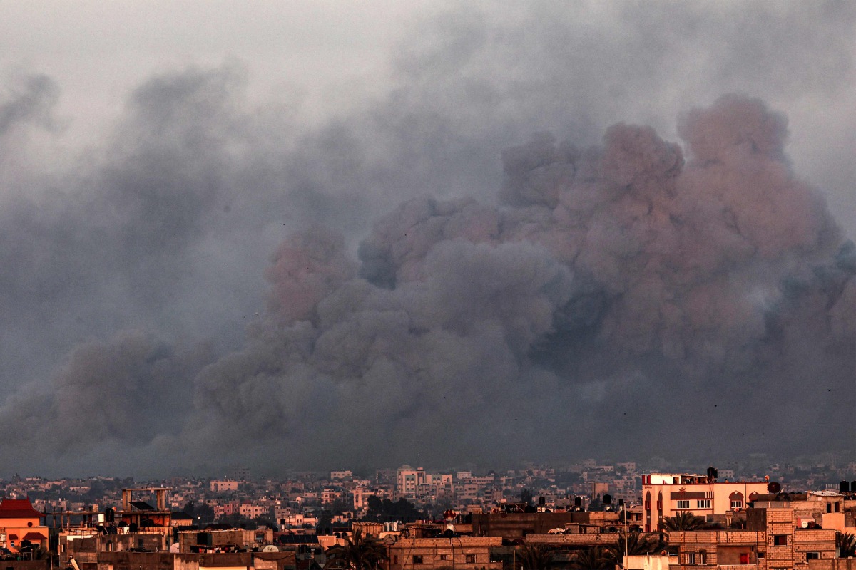 This picture taken from Rafah shows smoke billowing over Khan Yunis in the southern gaza Strip during Israeli bombardment on January 16, 2024 (Photo by Mahmud Hams / AFP)
