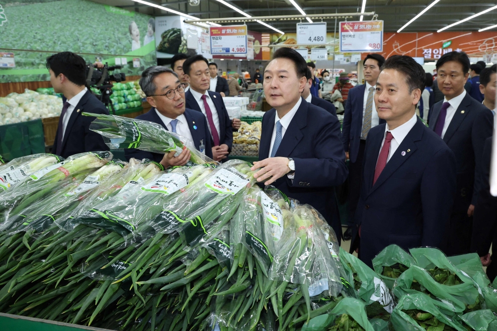 This picture taken on March 18, 2024 shows South Korean President Yoon Suk Yeol (C) visiting a Hanaro Mart branch to check the price of green onions in Seoul. Photo by YONHAP / AFP