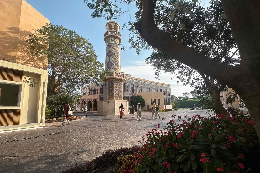 People walk around the Katara Mosque before sunset, which ushers 'Iftar' time when Muslims break their day-long fast during the holy month of Ramadan, at Katara Cultural Village in Doha on April 7, 2024. (Photo by KARIM JAAFAR / AFP)