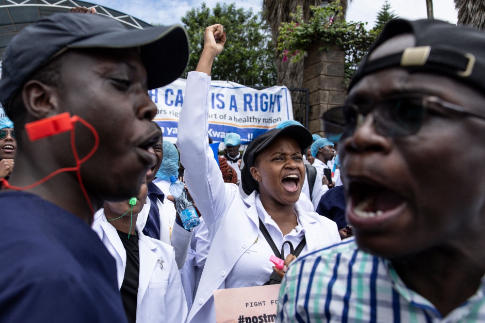 A Kenyan doctor gestures outside the health ministry headquarters while protesting with placards to demand better pay and working conditions in the capital, Nairobi on April 9, 2024. Photo by SIMON MAINA / AFP
