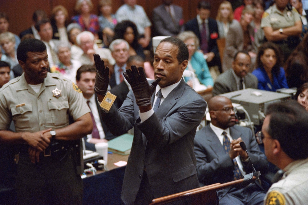 Double murder defendent OJ Simpson, looks at a new pair of Aris extra-large gloves which the prosecutors had him put on for the jury on June 21, 1995 during the OJ Simpson double murder trial in Los Angeles. (Photo by Vince Bucci / AFP)