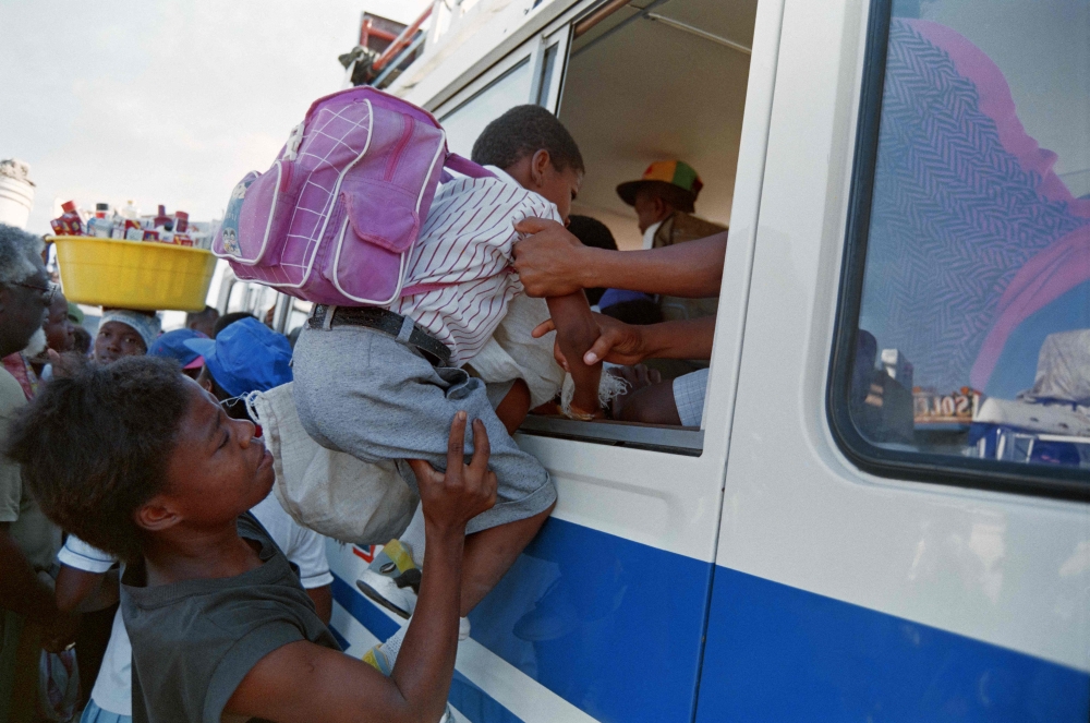 (FILES) A Haitian woman pushes her son through the window of a bus leaving for the countryside from Port-au-Prince on September 16, 1994. (Photo by Thony BELIZAIRE / AFP)
