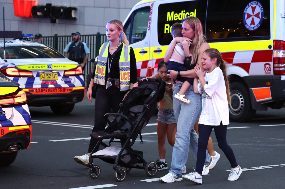 Families walk out of the Westfield Bondi Junction shopping mall after a stabbing incident in Sydney on April 13, 2024. (Photo by David Gray / AFP)