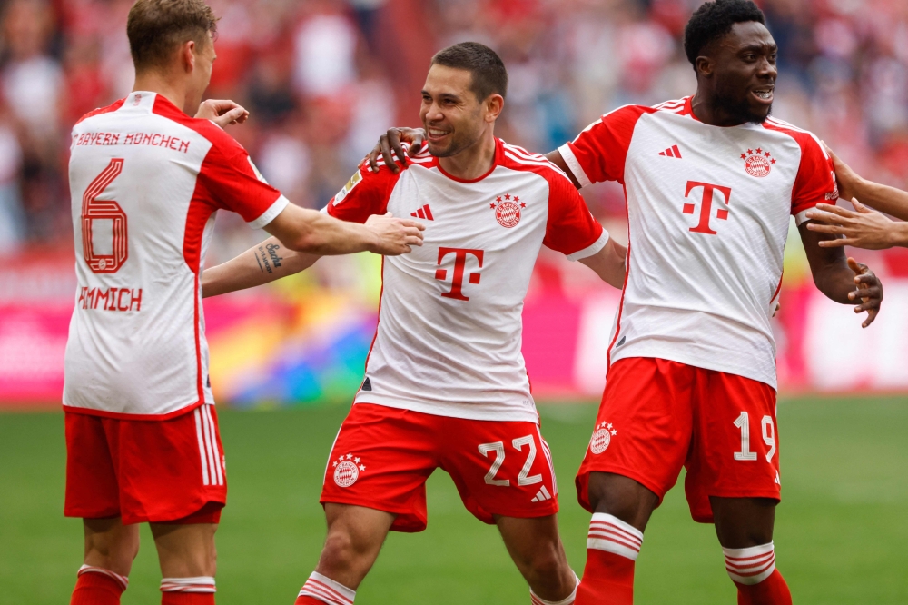 Bayern Munich's Portuguese defender #22 Raphael Guerreiro (C) celebrates scoring the opening goal with his teammates during the German first division Bundesliga football match between FC Bayern Munich and 1 FC Cologne in Munich, southern Germany on April 13, 2024. (Photo by Michaela STACHE / AFP)
