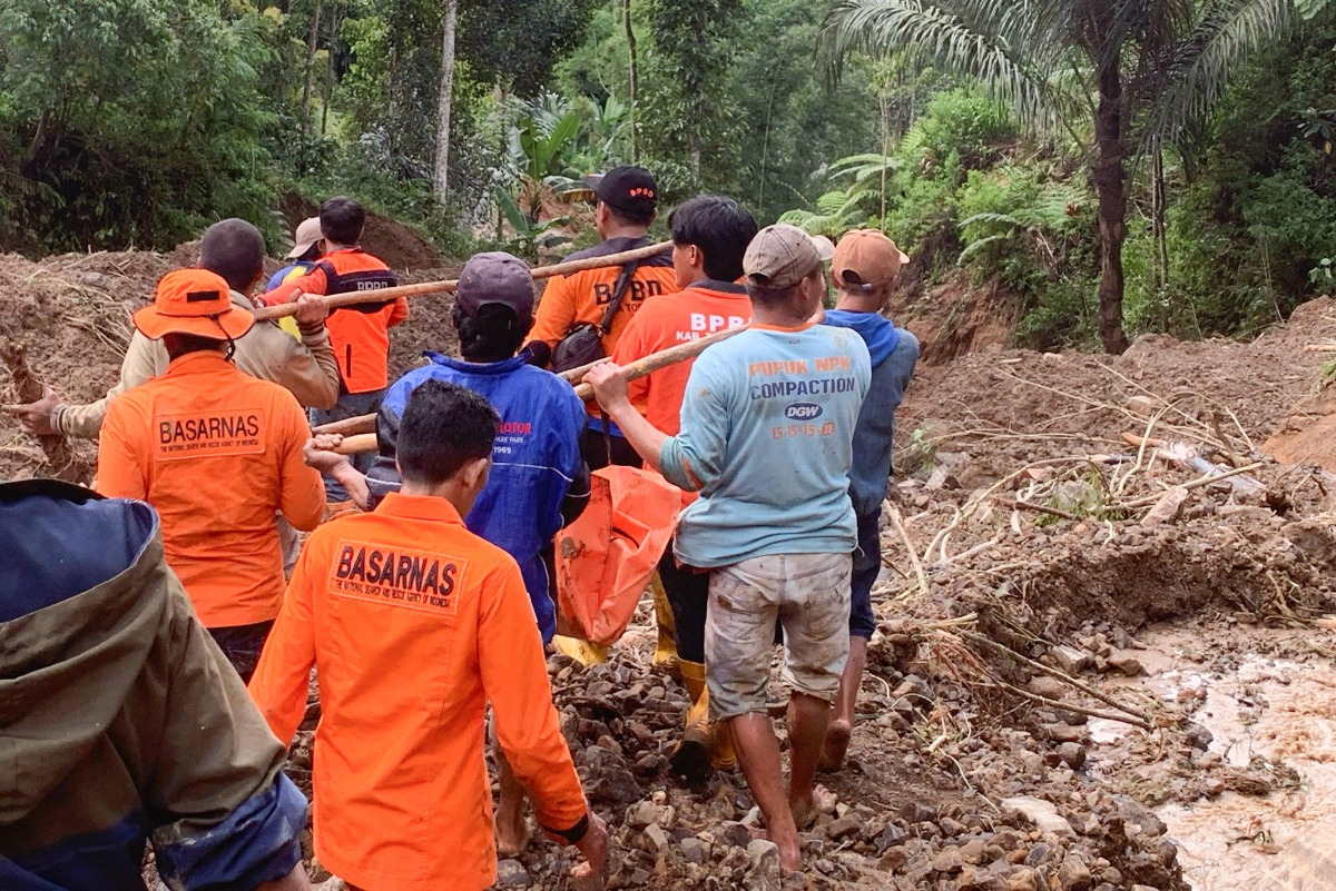 This handout photo released on April 14, 2024 by the National Search and Rescue Agency (BASARNAS) shows rescuers carrying a body bag at a landslide site in Tana Toraja, South Sulawesi. At least 19 people have been found dead and two more are missing after a landslide in central Indonesia, local authorities said on April 14. (Photo by Handout / BASARNAS / AFP)