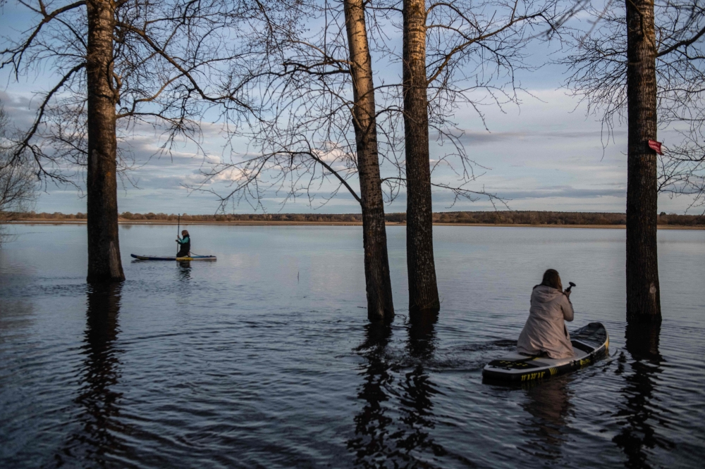 People sail on paddleboards in floodwater from the overflowing Nerl River outside the settlement of Bogolyubovo in the Vladimir region on April 13, 2024. Photo by Valery MELNIKOV / AFP