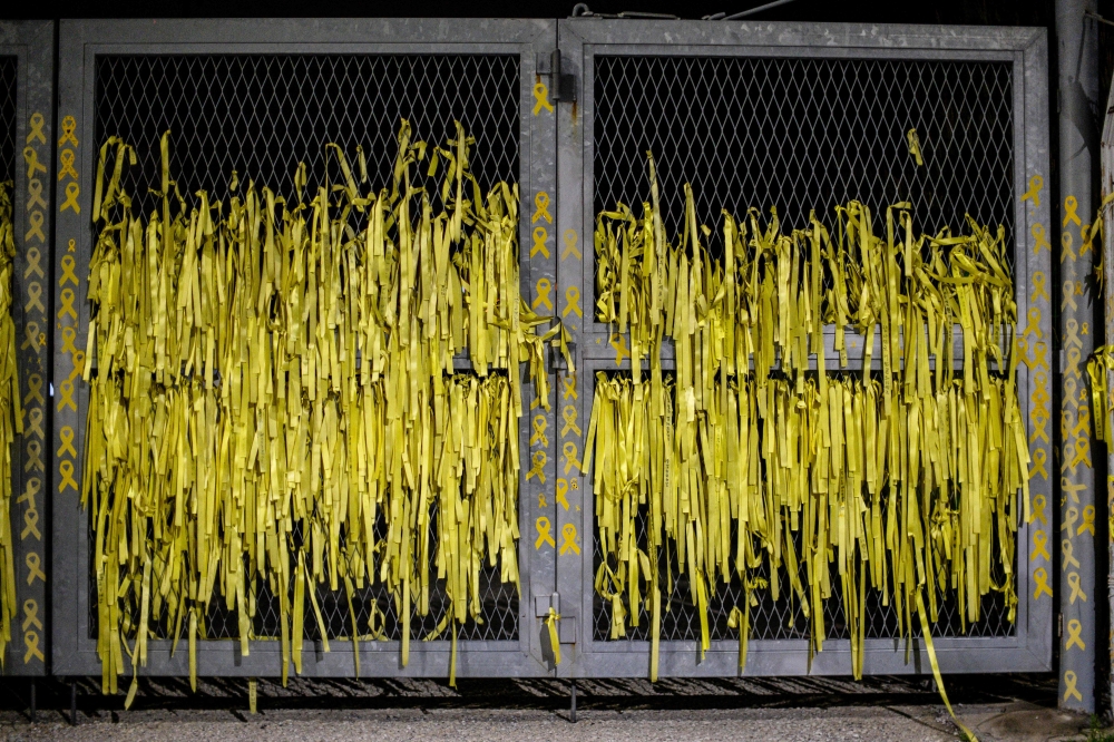 Yellow ribbon dedications are displayed on the main gates at a port in Mokpo, South Jeolla Province, near to where the salvaged Sewol ferry stands, late on April 15, 2024, on the eve of the 10th anniversary of the country's worst-ever maritime disaster on April 16, 2014, when the overloaded Sewol ferry capsized off South Korea's southern coast. (Photo by ANTHONY WALLACE / AFP)