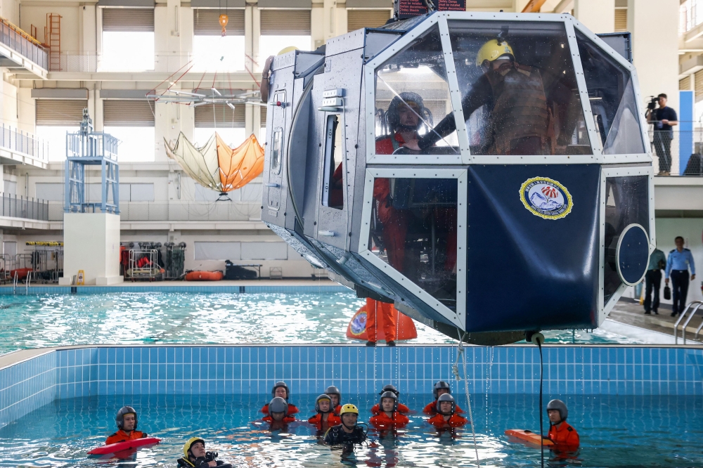 Taiwanese air force personnel take part in water survival and aviation egress training in a specialised pool at a base in Kaohsiung on April 17, 2024. (Photo by I-Hwa CHENG / AFP)