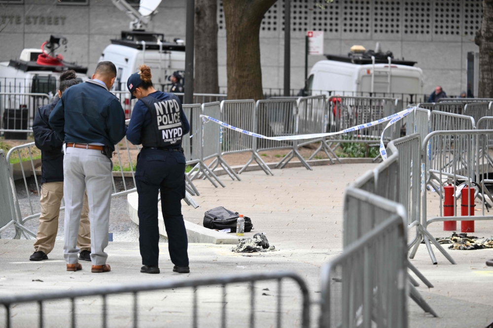 Law enforcement officials investigate the scene after a man reportedly set himself on fire in the park across from Manhattan Criminal Court on April 19, 2024. (Photo by Angela Weiss / AFP)