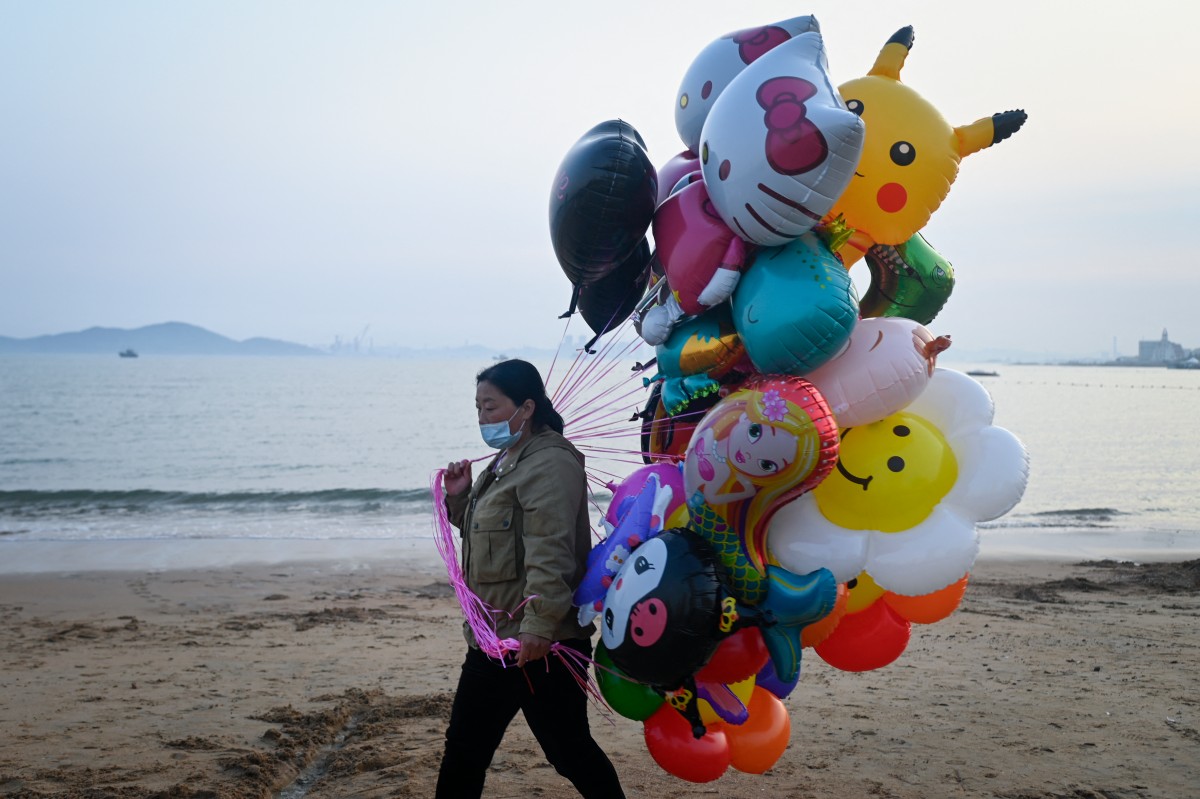 A balloon vendor walks on the beach in Qingdao, China's Shandong province on April 21, 2024. (Photo by WANG Zhao / AFP)
