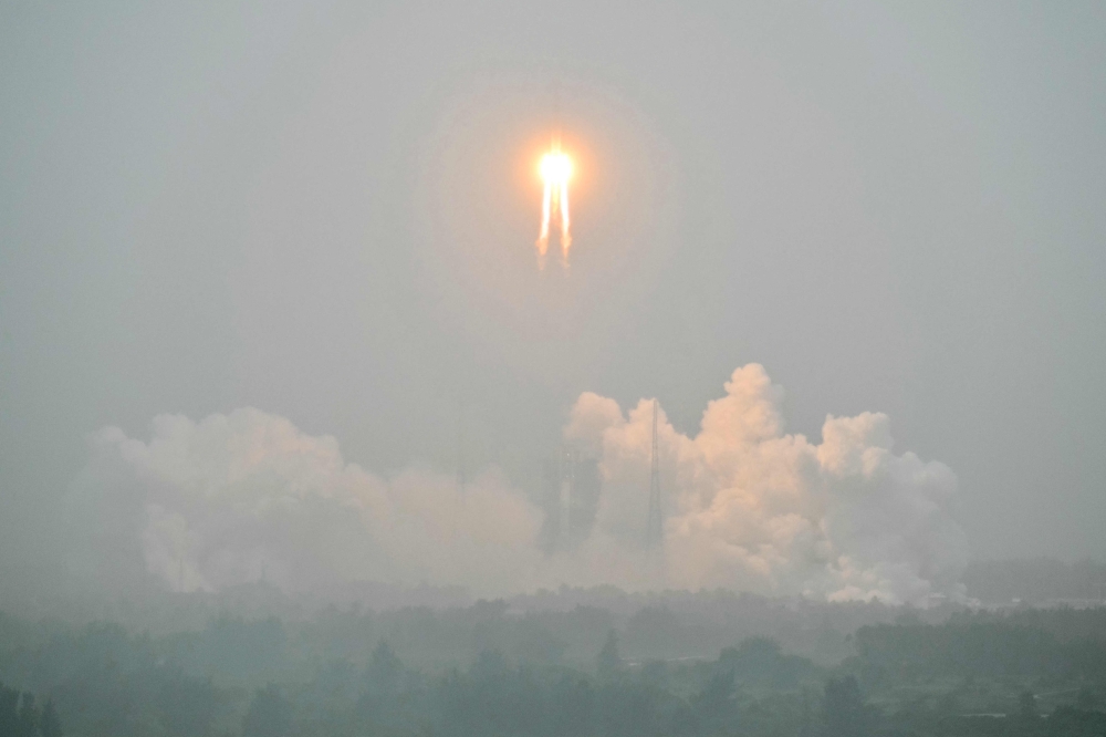 A Long March 5 rocket, carrying the Chang'e-6 mission lunar probe, lifts off as it rains at the Wenchang Space Launch Centre in southern China's Hainan Province on May 3, 2024. Photo by HECTOR RETAMAL / AFP