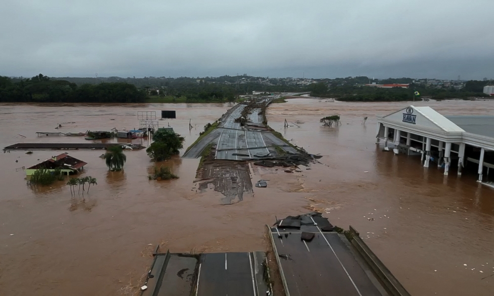 Grab from a handout video released by the Sao Paulo Civil Defense showing the flooded Taquari river bridge, which is part of the BR-396 highway that connects the cities of Lageado and Estrela, in the region of Vale do Taquari, Rio Grande do Sul state, Brazil on May 3, 2024. (Photo by Handout / Sao Paulo Civil Defense / AFP)