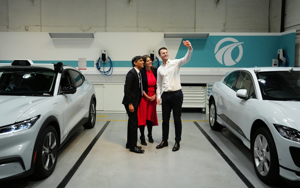 Britain's Prime Minister Rishi Sunak and Britain's Science, Innovation and Technology Secretary Michelle Donelan pose for a selfie photograph with Wayve Technologies co-founder and CEO Alex Kendall and an autonomous car, during a visit to the offices of the automated driving technology company, in London on May 7, 2024. Photo by Carl Court / POOL / AFP.