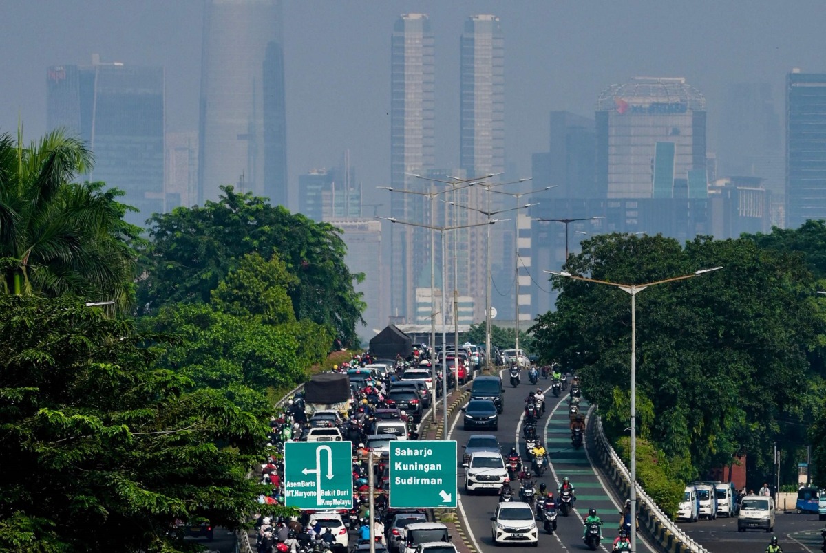 This photo shows a general view of a traffic jam on a main roads leading into the city center of Jakarta on May 8, 2024 as thin haze of pollution sits over the city's skyline. (Photo by BAY ISMOYO / AFP)
