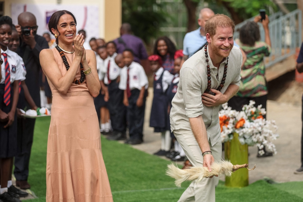 Britain's Prince Harry (R), Duke of Sussex, and Britain's Meghan (L), Duchess of Sussex, take part in activities as they arrive at the Lightway Academy in Abuja on May 10, 2024 as they visit Nigeria as part of celebrations of Invictus Games anniversary. (Photo by Kola SULAIMON / AFP)

