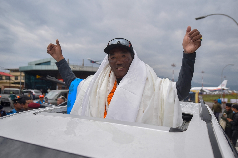 (Files) Nepali guide Kami Rita Sherpa who reached the top of Mount Everest on May 23, 2023, for a record 28th time gestures to the crowd upon arriving at the Tribhuvan airport in Kathmandu on May 25, 2023. (Photo by Nisha Bhandari / AFP)

