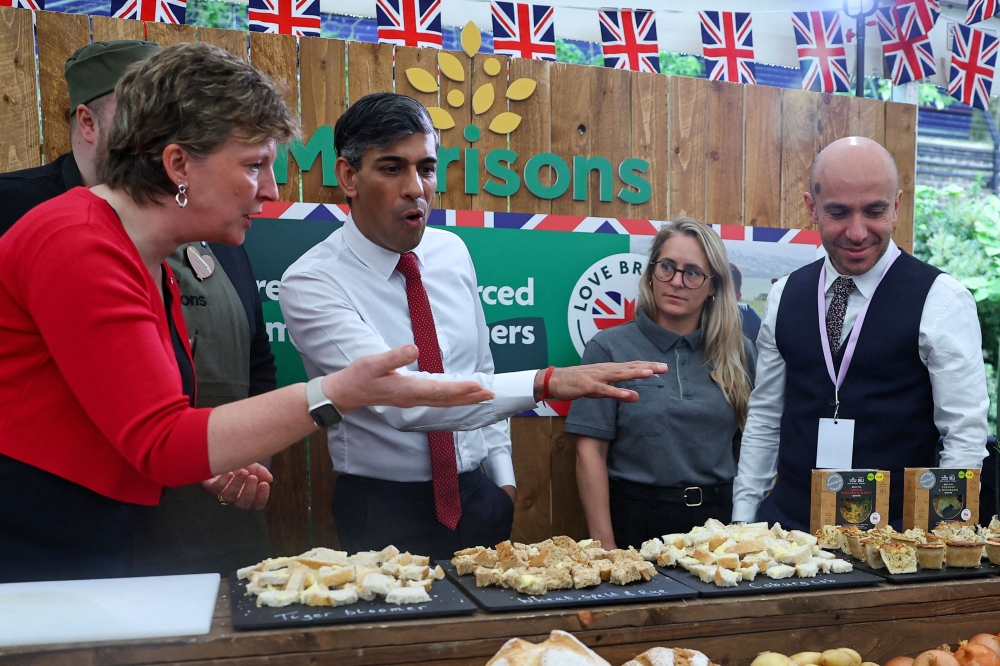 Britain's Prime Minister Rishi Sunak talks to employees of Morrison Supermarkets as he visits stalls during a 'Farm to Fork' summit in Downing Street, central London on May 14, 2024. Photo by Toby Melville / POOL / AFP.