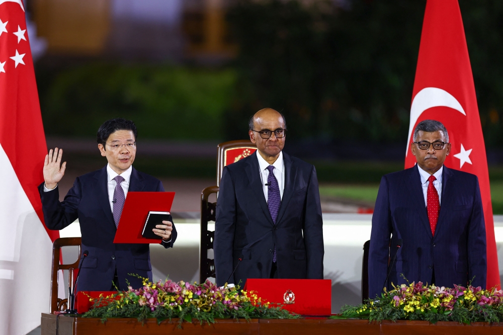 Singapore's incoming Prime Minister Lawrence Wong (L) is sworn in next to President Tharman Shanmugaratnam and Chief Justice Sundaresh Menon at the Istana in Singapore on May 15, 2024. (Photo by Edgar Su / Pool / AFP)
 