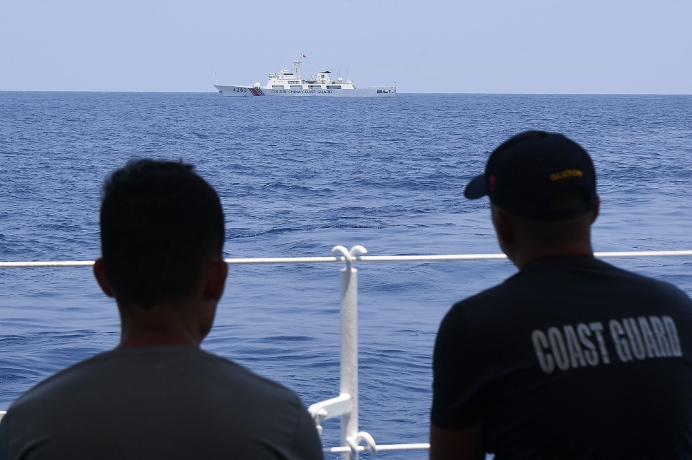 Philippine Coast Guard personnel aboard BRP Bagacay observe a China Coast Guard ship during the distribution of fuel and food to fishers by the civilian-led mission Atin Ito (This Is Ours) Coalition, in the disputed South China Sea on May 16, 2024. Photo by Ted ALJIBE / AFP