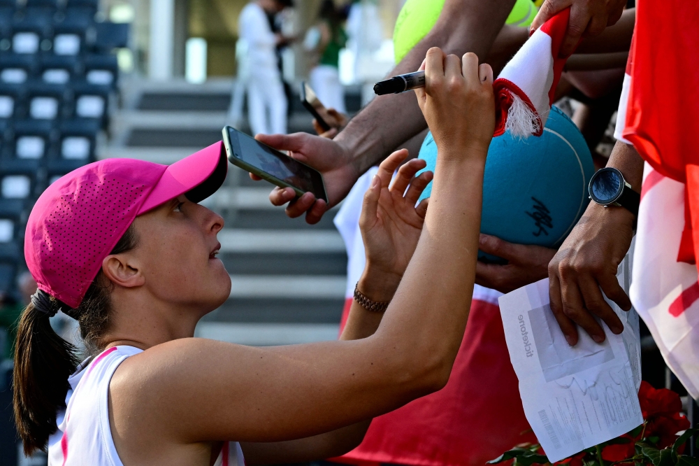 Poland's Iga Swiatek signs autographs after winning against USA's Coco Gauff at the Women's WTA Rome Open tennis tournament at Foro Italico in Rome on May 16, 2024. (Photo by Tiziana Fabi / AFP)