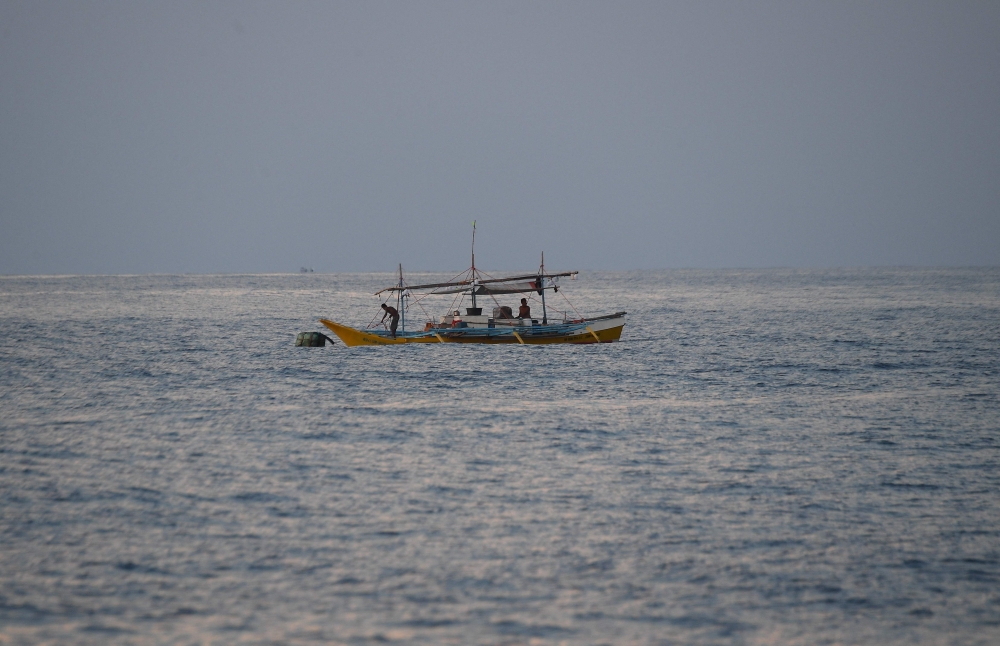 In this photo taken on May 16, 2024, Philippine fishermen aboard their wooden boat catch fish in South China Sea. (Photo by Ted Aljibe / AFP)