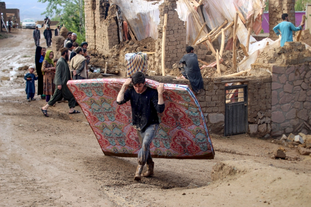 Afghan residents clean debris and salvage their belongings after flash floods following heavy rainfall at a damaged house in Firozkoh, Ghor province on May 18, 2024. Photo by AFP