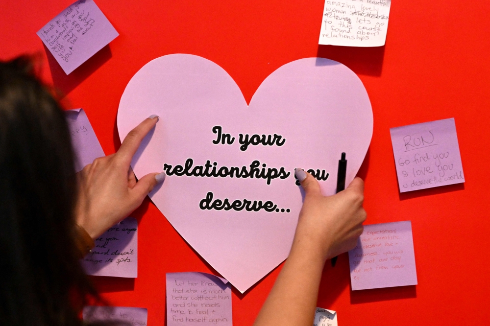 This picture taken on May 8, 2024 shows Shazya Singh, domestic and family violence case manager at Lou's Place that provides daytime shelter to women seeking support from domestic violence, pasting messages on a chart at the shelter in Sydney. Photo by Saeed KHAN / AFP