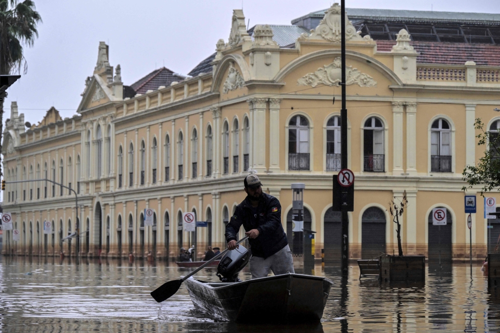 A man navigates a boat through a flooded street in front of the public market in downtown Porto Alegre, Rio Grande do Sul State, Brazil, on May 19, 2024. Photo by Nelson ALMEIDA / AFP