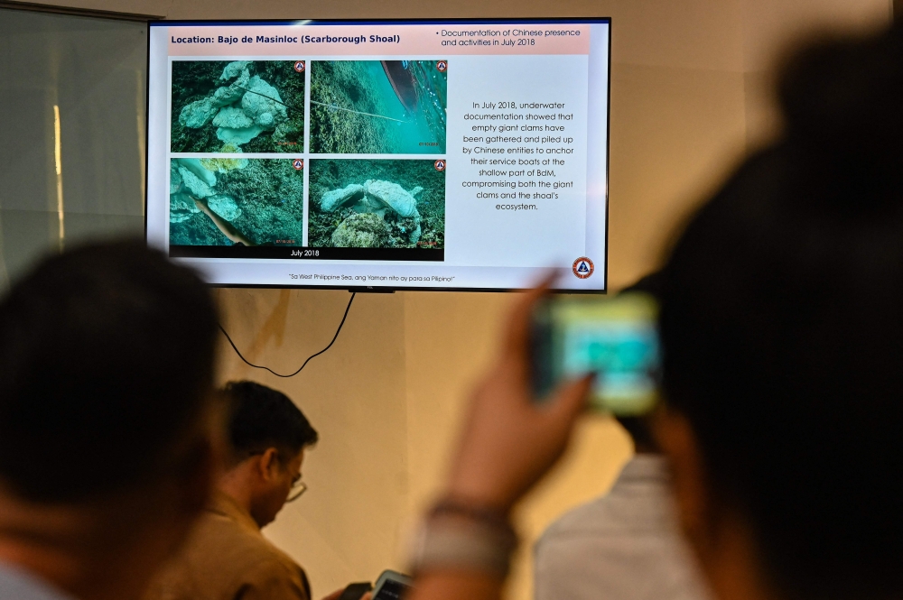 A journalist takes a photo of a presentation by the Philippine Coast Guard showing alleged Chinese activities in Scarborough Shoal, during a press conference in Manila on May 20, 2024. (Photo by JAM STA ROSA / AFP)