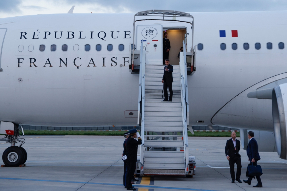 France's President Emmanuel Macron waves as he boards his Presidential aeroplane to travel to the Pacific archipelago of New Caledonia in an attempt to resolve a political crisis, at the Orly airport, suburb of Paris on May 21, 2024. Photo by Ludovic MARIN / POOL / AFP.