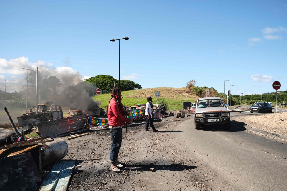 People man a roadblock barricade, with Kanak flags, controlling access to a district in Noumea, France's Pacific territory of New Caledonia, on May 24, 2024. (Photo by Theo Rouby / AFP)